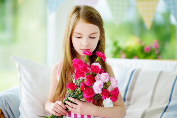 Adorable smiling little girl holding flowers for her mom on mother's day