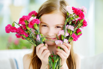 Adorable smiling little girl holding flowers for her mom on mother's day