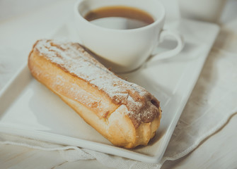 Chocolate eclair on the plate and cup of coffee