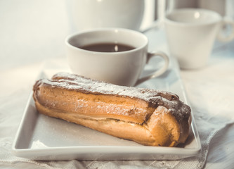 Chocolate eclair on the plate and cup of coffee