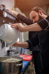 Male chef in black uniform cooking cream