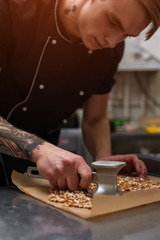 Male cook cracking caramelized almonds, closeup