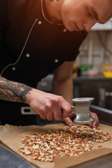 Male cook cracking caramelized almonds, closeup