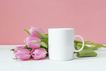 Fototapeta na wymiar White coffee mug with pink tulips on a pink background. Space fo