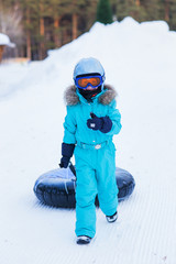 cheerful girl in a helmet and glasses riding on a sled with high mountains
