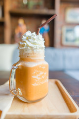 ice tea with milk in Glass handle Thailand style on wooden table.