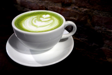 Matcha green tea latte cup on brick wall background