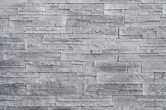 Grey stone wall background. Stacked stone tiles are often used in interior design decors as accent wall. Use this gray texture in graphic design to create a wallpaper, background, backdrop and more!