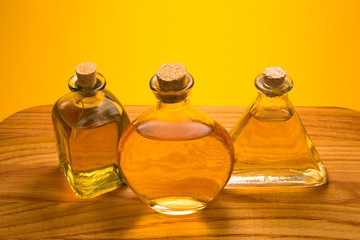 Obraz na płótnie Canvas Three vintage glass bottles with yellow liquid on wooden desk on bright orange background