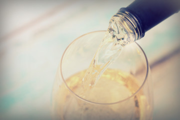 Glass of white wine being poured from bottle