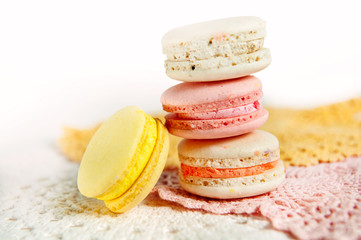 Pink, yellow and white macaroons on pastel colored lace background