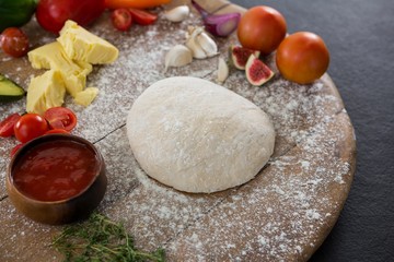 Fototapeta premium Various ingredients with pizza dough and flour on rolling board