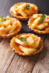 Tartlets with pineapple, jam and mint close-up. vertical