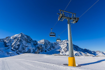 Ski winter season, ski run and chairlift in Italian Alps. Solda with Ortler, Zebru, Grand Zebru in background. Val Venosta, South Tirol, Italy.
