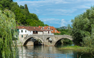 Fototapeta na wymiar Old bridge and houses in the city of River Crnojevica. Bridge re