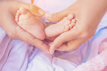 Baby feet in the mother hands. Heart shape.