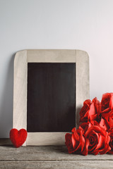 Love hearts shape, red roses and empty chalk board on wood backg