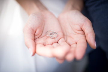 Closeup silver wedding rings in hands of woman and bride