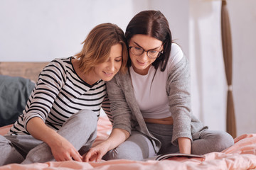 Focused charming friends reading a magazine together