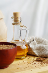 Flax seeds on spoon and in wooden bowl. Linseed oil in glass jug