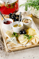 assorted cheeses with honey, jam, nuts and grapes