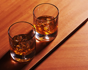 Highball whiskey glass with ice on wooden background. Closeup.