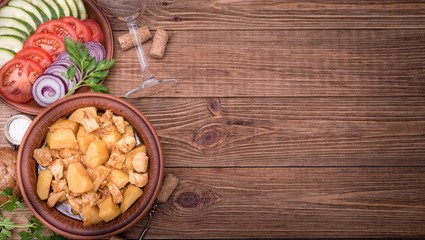 Meat stewed with potatoes in bowl on wooden background.