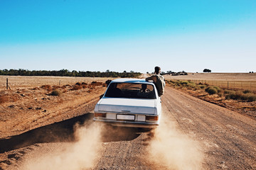 Obraz na płótnie Canvas 3 guys on a road trip along a Rural dirt road in the desert.