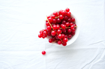 Fresh red currant in a small bowl on a white background