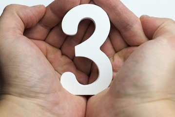 Hands on a white background holding number 3
