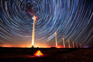 Kreise am Nachthimmel / Langzeitbelichtete Nachtlandschaft mit Sternenspuren über einem Windpark