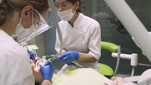 Dentists treat tooth girl. Teeth whitening. 60fps. Close-up.
