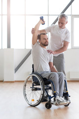 Powerful disabled man exercising with his coach in the gym