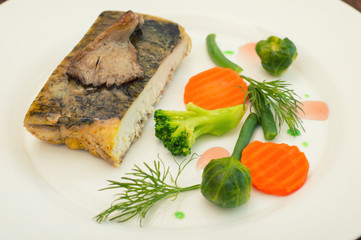 Tasty baked fish on plate on table close-up. Wooden background. Top view. Close-up