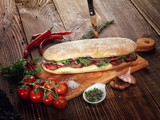 Sandwich with beef steak on a wooden stand.
