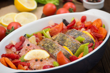 Sea bass with vegetables. marinated fish with vegetables for cooking in the oven. Wooden background. Top view. Close-up