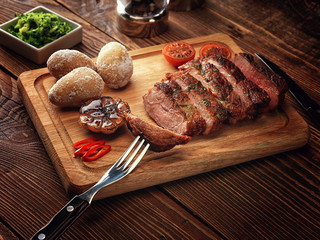 Roasted pork steak cut into slices on a wooden stand.