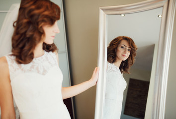The bride looks at mirror in the room