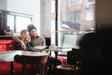 Side view of happy hipsters looking at laptop