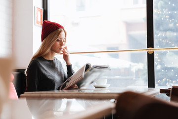 Side view of concentrated woman in cafe with journal