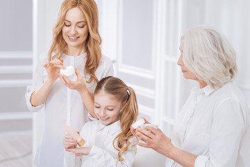 Obraz na płótnie Canvas Joyful smiling family members using cosmetics