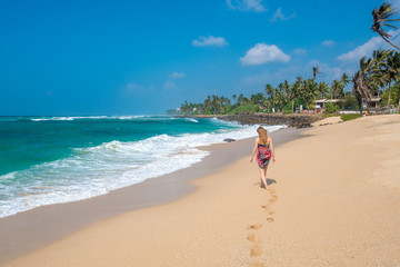 Beautiful young woman walking on ocean shore