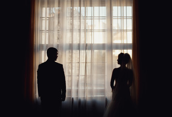 young couple standing on the background of window
