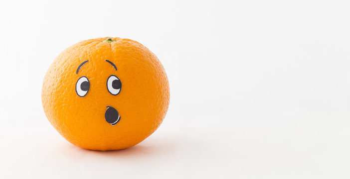 An orange in front of white background with a funny face showing astonishment