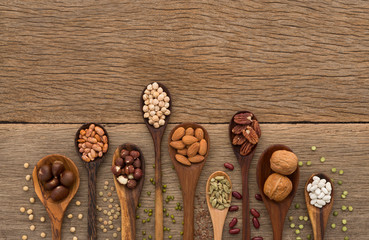 Different kind of beans and lentils in wooden spoon on wood back