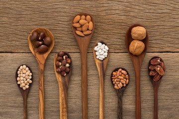 Different kind of beans and lentils in wooden spoon on wood back