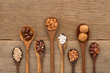 Different kind of beans and lentils in wooden spoon on wood back