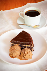 Chocolate cake with ice cream and cup of coffee. Selective focus on cake