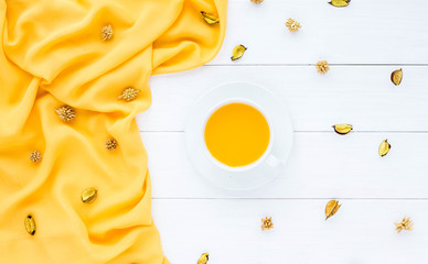 Composition with orange juice, yellow shawl, flowers on white wooden background. Flat lay, top view 