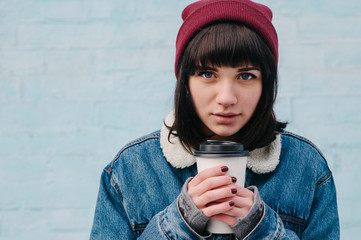 portrait of a young girl hipster heated coffee and smiling